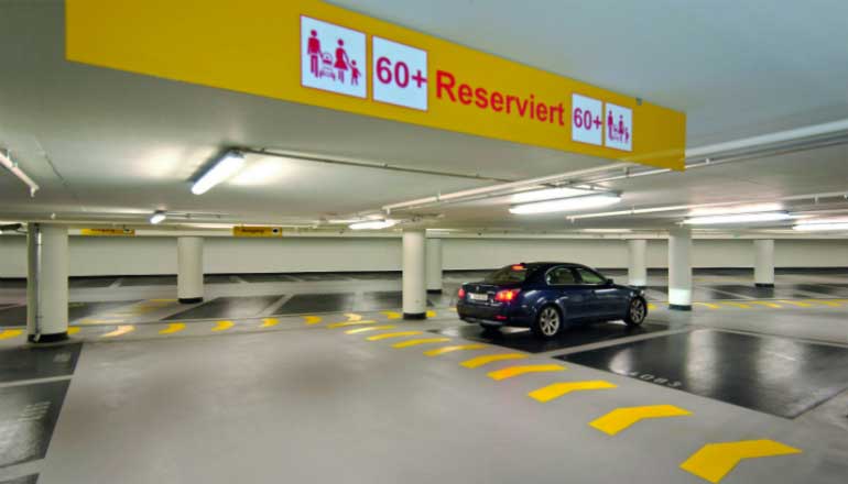 Ein gelbes Schild im Parkhaus weist Parkplätze für Senioren aus.